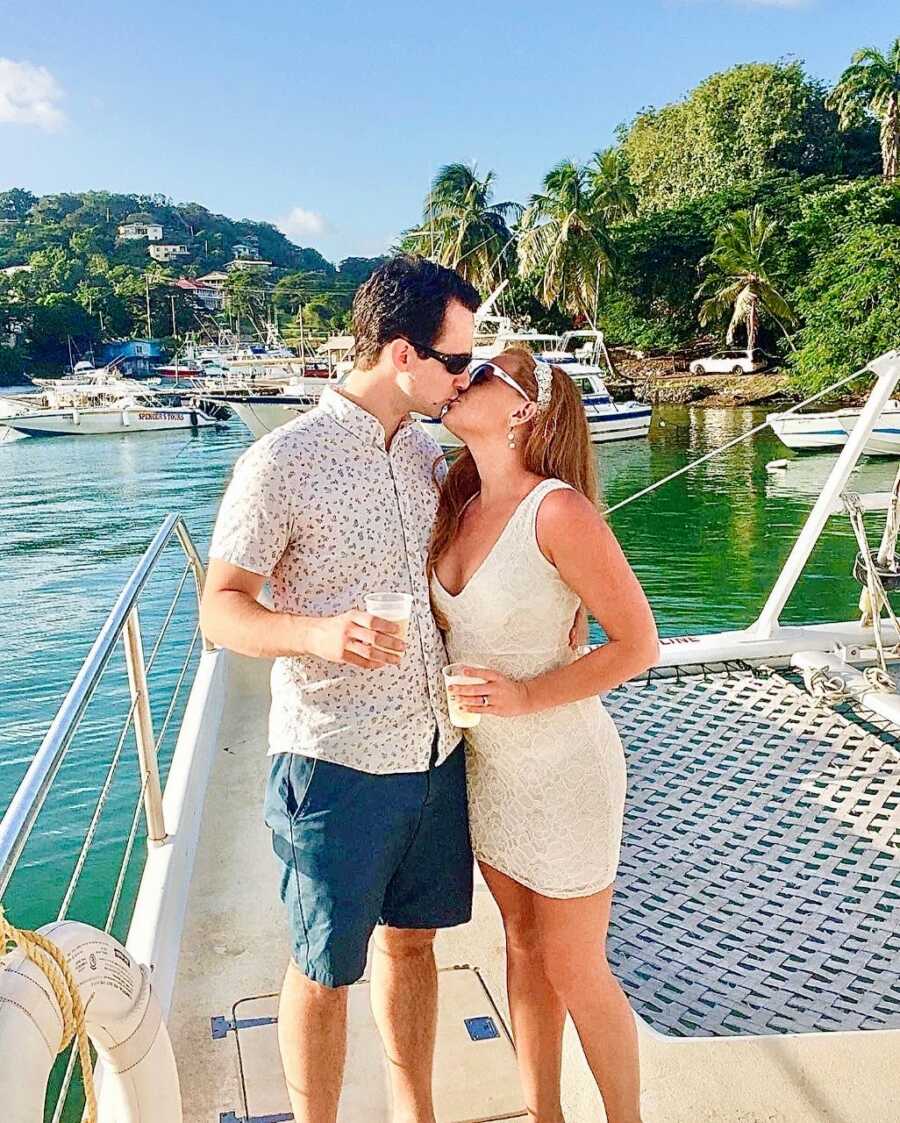 Couple share a kiss while on a boat during their honeymoon