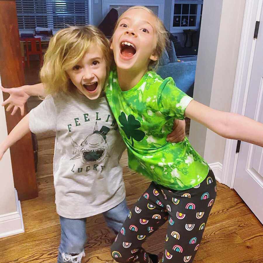 two kids screaming looking excited and hugging each other at home 