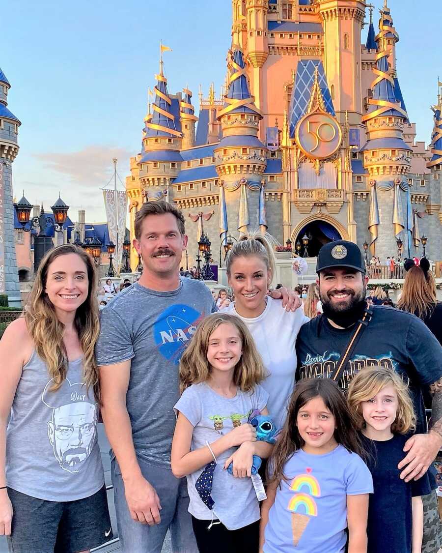 Lesbian mom and her blended family at Disney world in front of the castle 