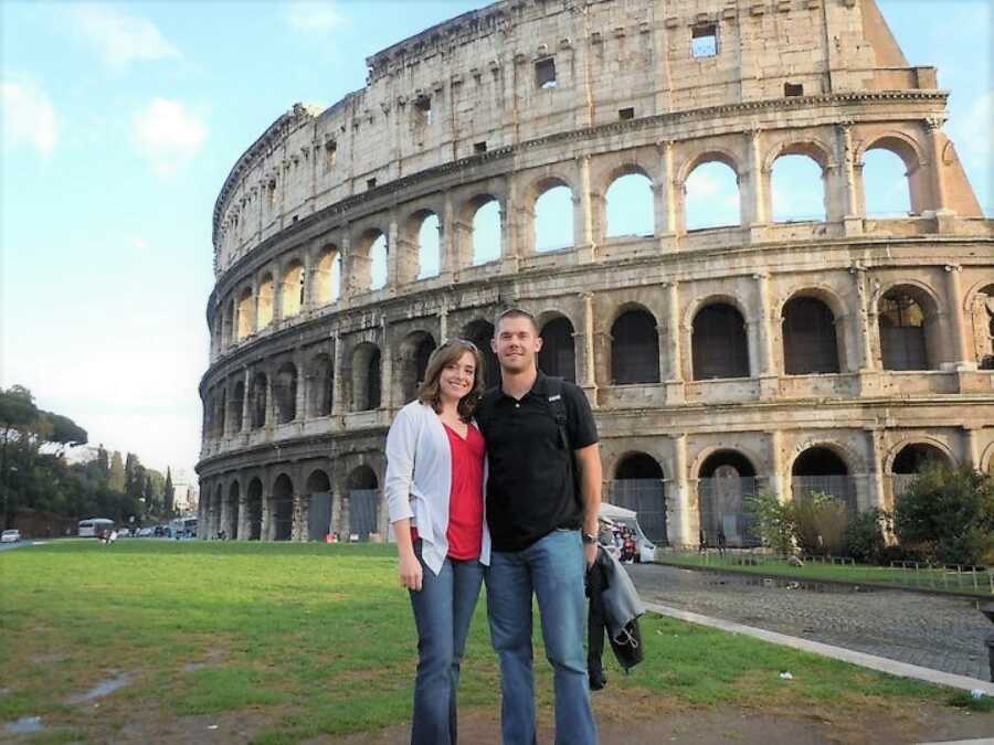 couple standing in front of the Colosseum in Rome, Italy