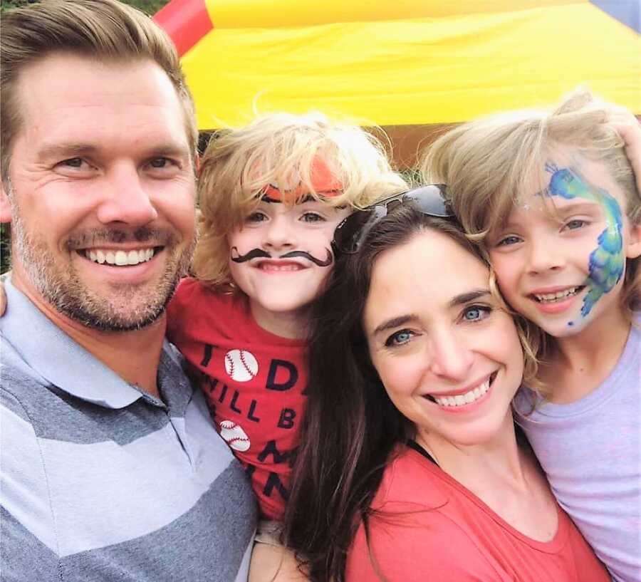 Lesbian mom co-parenting after divorce spending time with their kids at a playground with their faces painted 