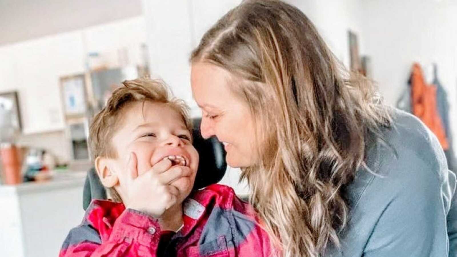 Special needs mom smiles at her son while he smiles back at her