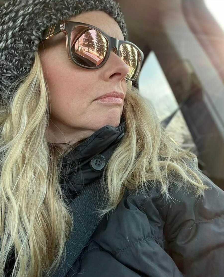 Woman reflecting on her life journey takes a reflective selfie in her car