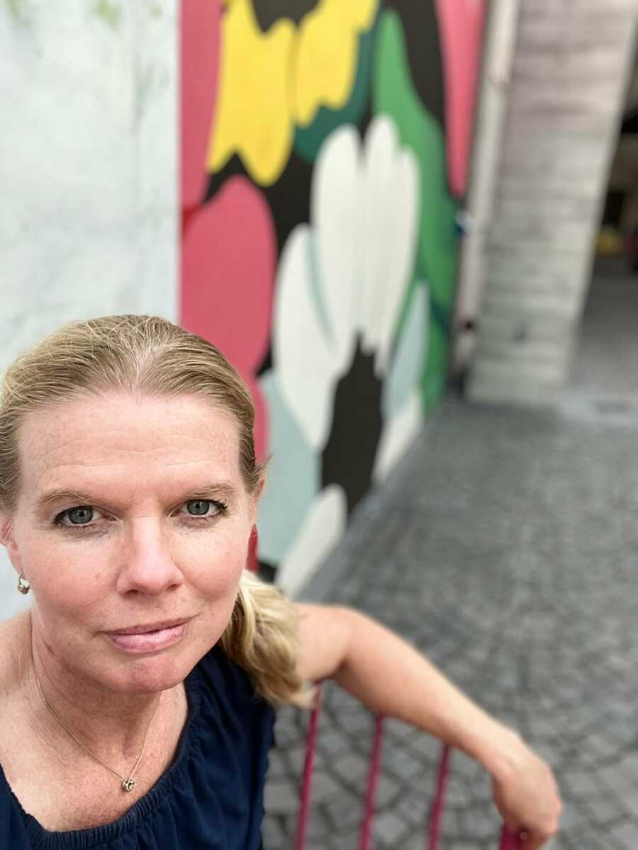 mom takes a selfie in front on street art painting of flowers 