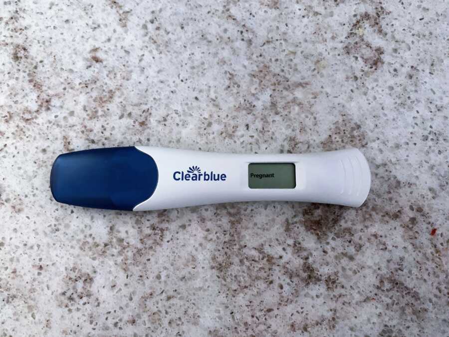 Positive Clear Blue pregnancy test laying on marble countertop 