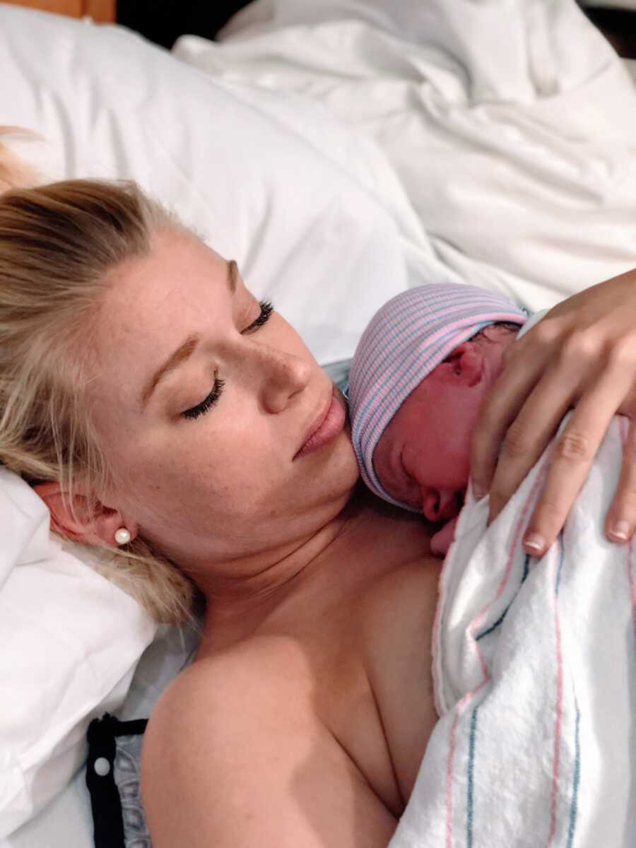 First time mom looks solemn while holding newborn baby girl