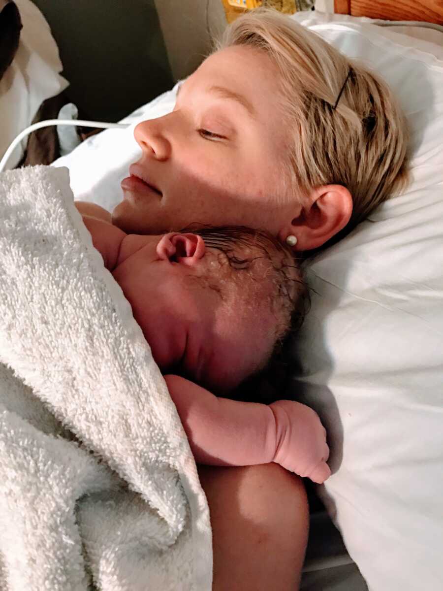 First time mom holds newborn in hospital bed after giving birth
