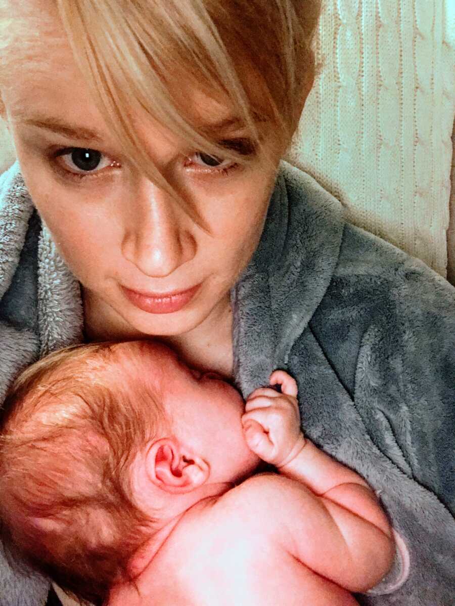 Mom takes selfie looking sad and tired while holding newborn daughter