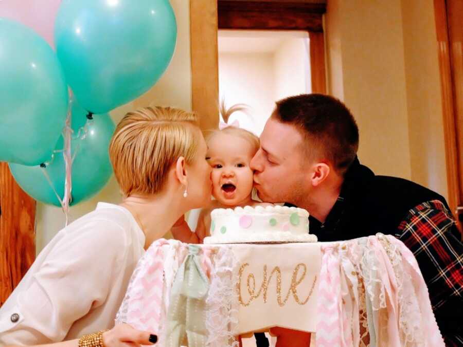 New parents kiss their daughter's cheeks on her first birthday