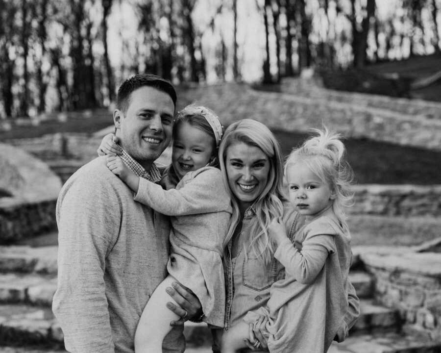 Family of four take a photo together in front of a barn