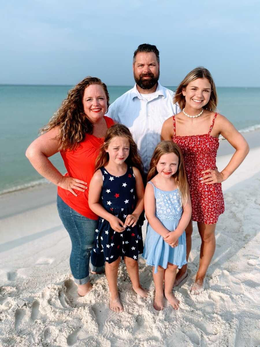 Family of five take photos on the beach together in red, white, and blue while celebrating Independence Day
