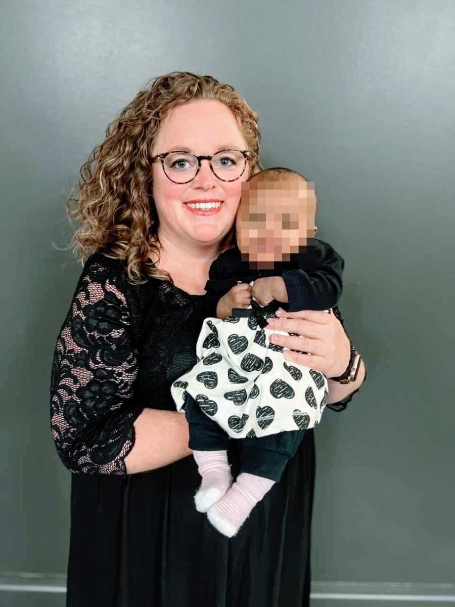 Mom holds baby foster daughter while both dressed in black dresses