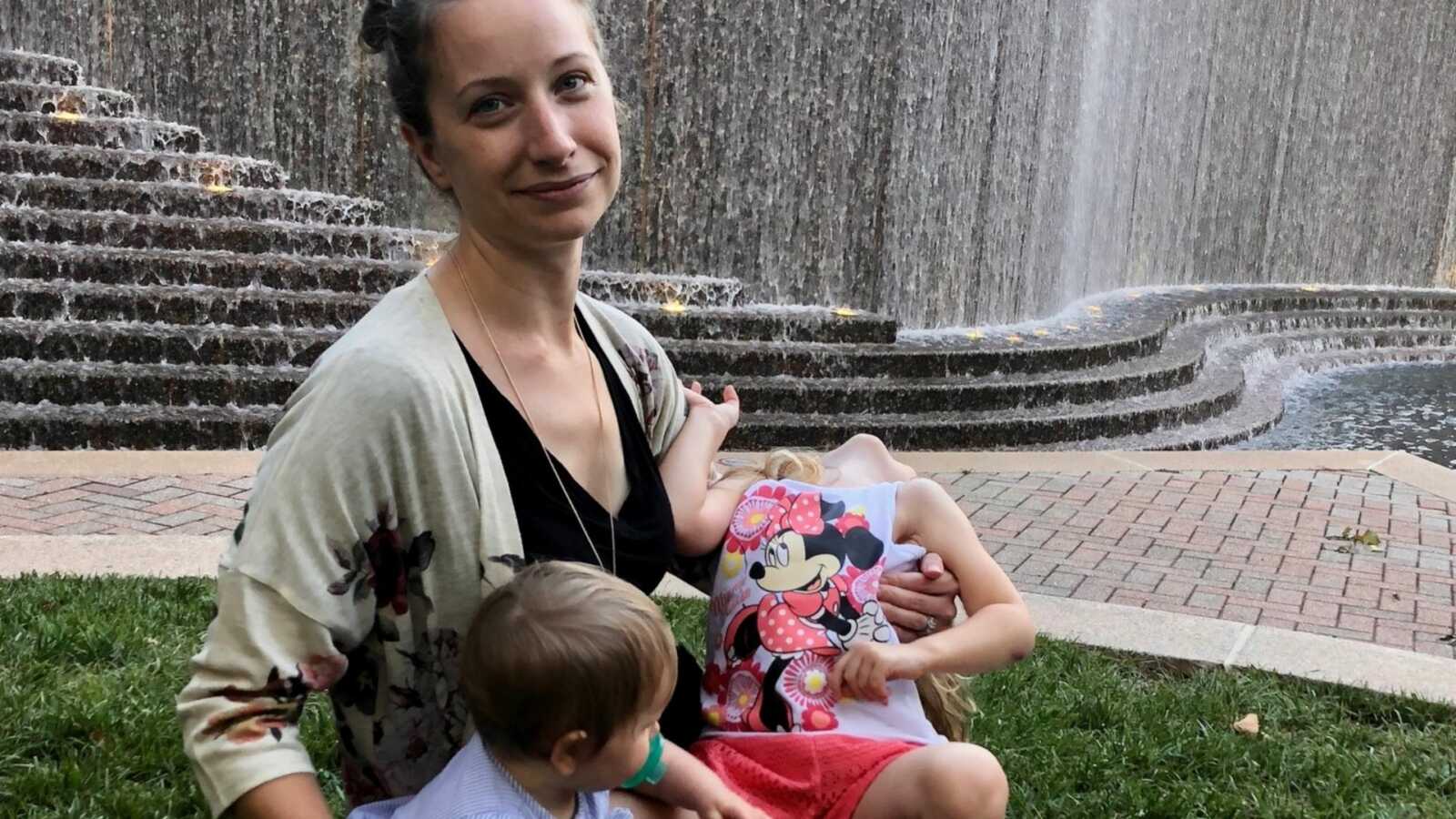 mom holding both of her kids by steps