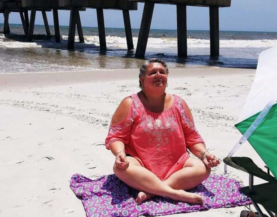 woman meditating on the beach