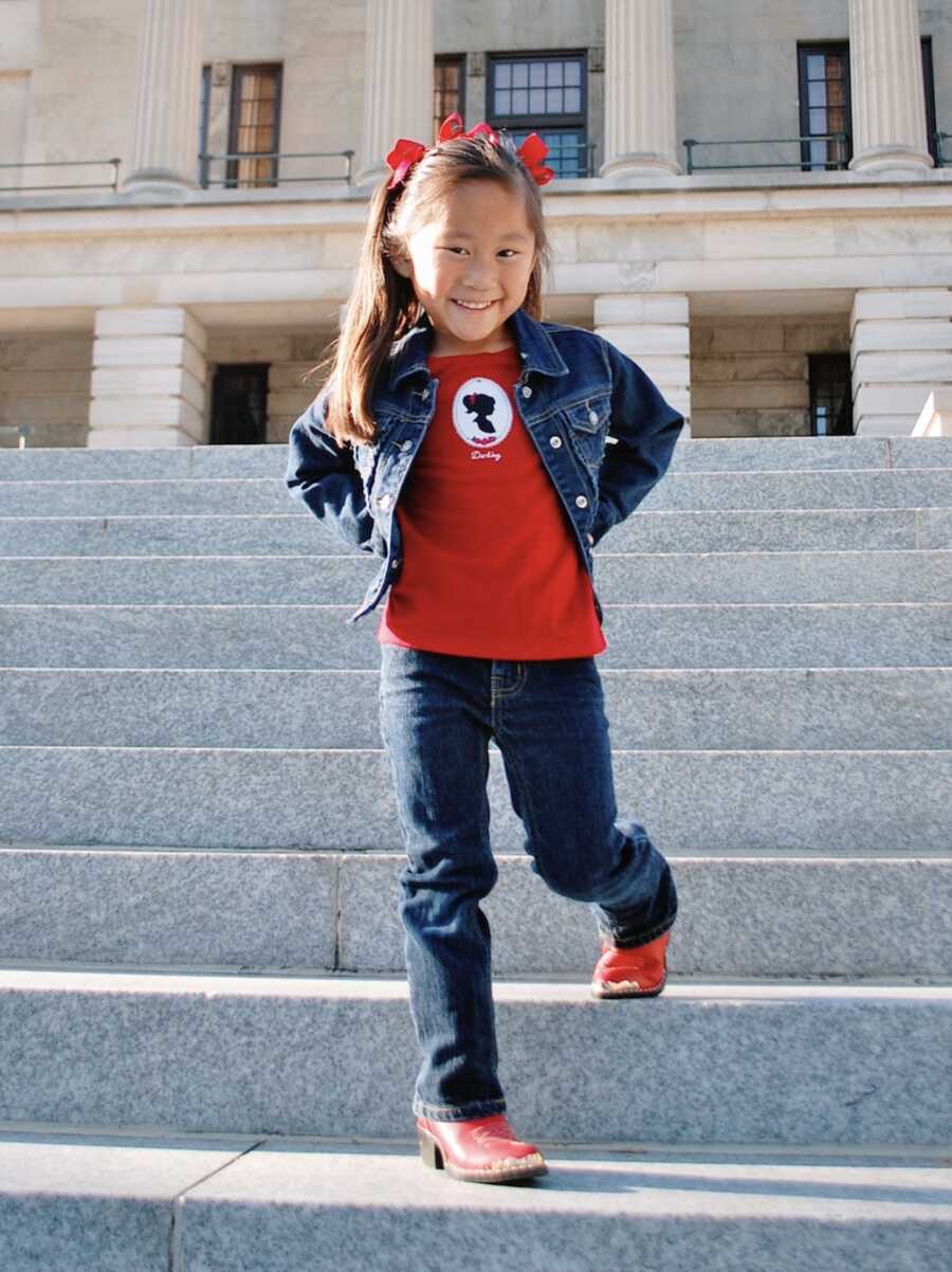 Chinese girl adopted by Nashville woman takes picture in cute western outfit. 