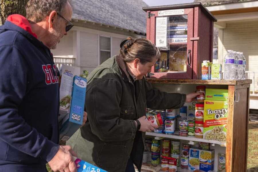 Couple puts food items in little free pantry they created during COVID.