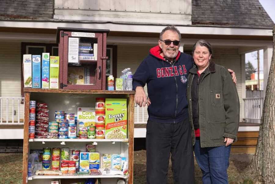 Couple stands next to free food pantry they set up in their front yard.