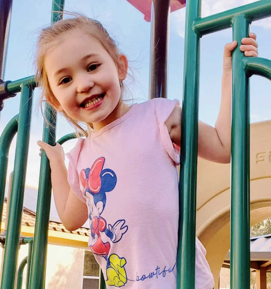 young girl plays on a playground and is smiling