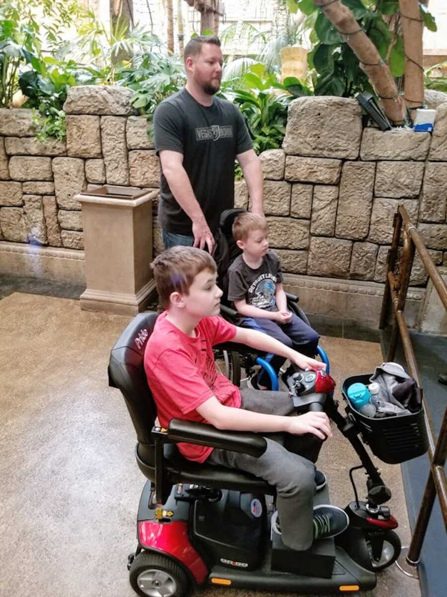 Duchenne dad stands behind his two sons with Duchenne's in wheelchairs