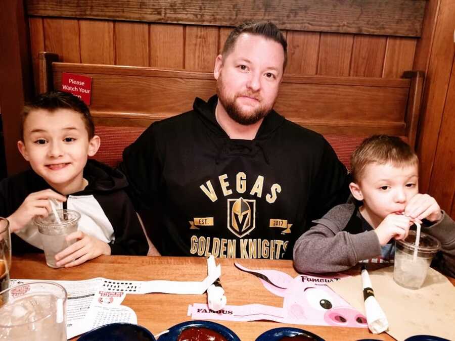 Duchenne dad sits at a booth in a restaurant with his two sons with Duchenne's