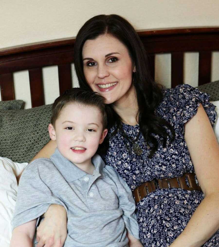 Duchenne mom puts her arm around her son with Duchenne's while both are smiling