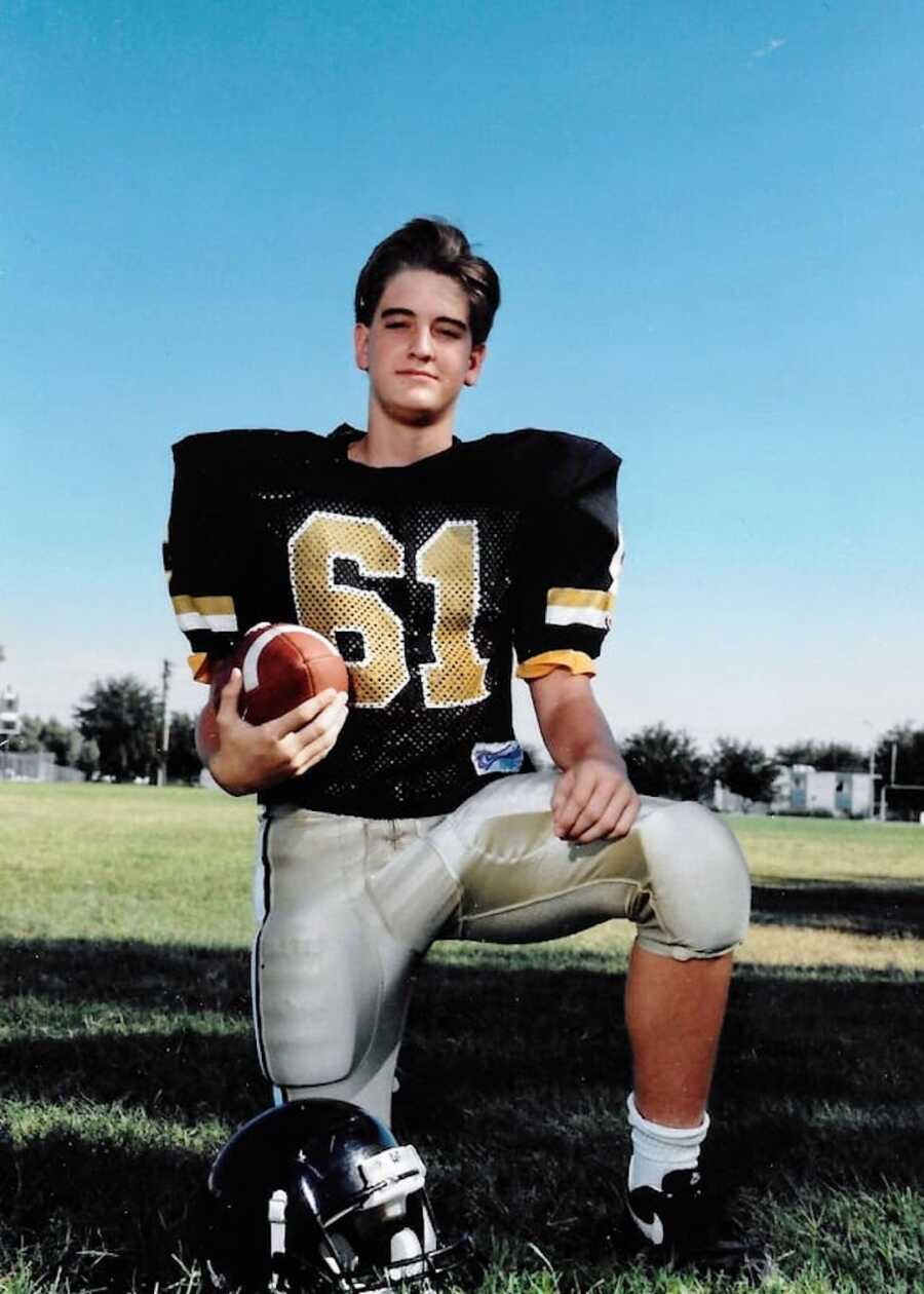 old image of brother who has passed in his football uniform on one knee holding a ball