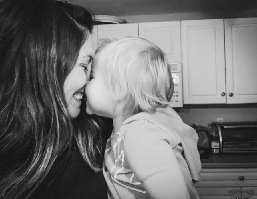 mom smiling and kissing her daughter