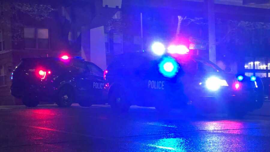 Police cars with flashing lights wait outside house.