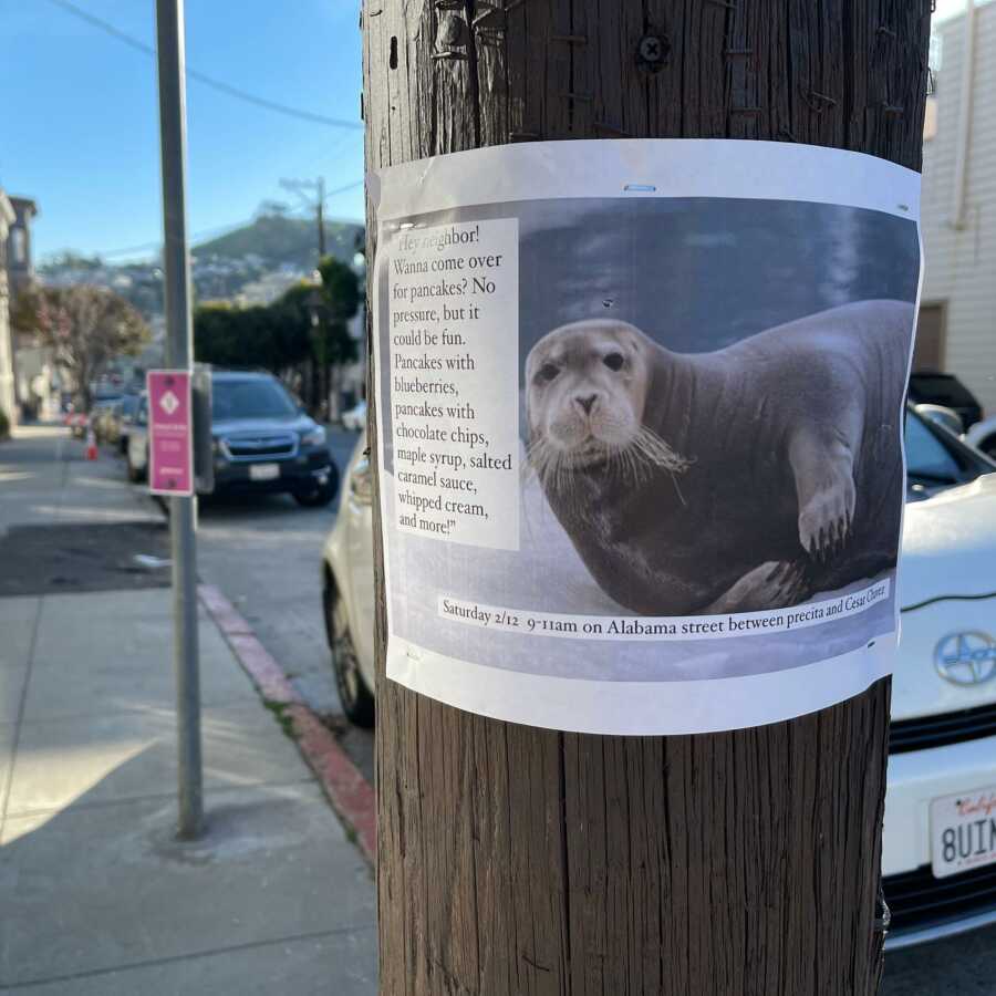 Flyer with picture of sea lion and information about a pancake party stapled to a wooden pole. 