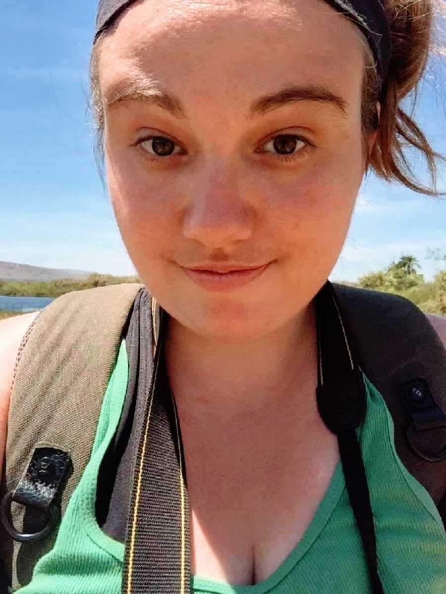 A young single woman wearing a green shirt and a camera around her neck