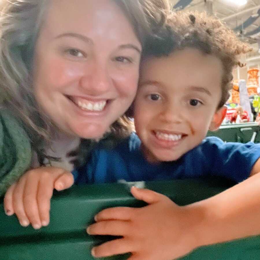 A single mom and her five-year-old son stand in a store by a green wall