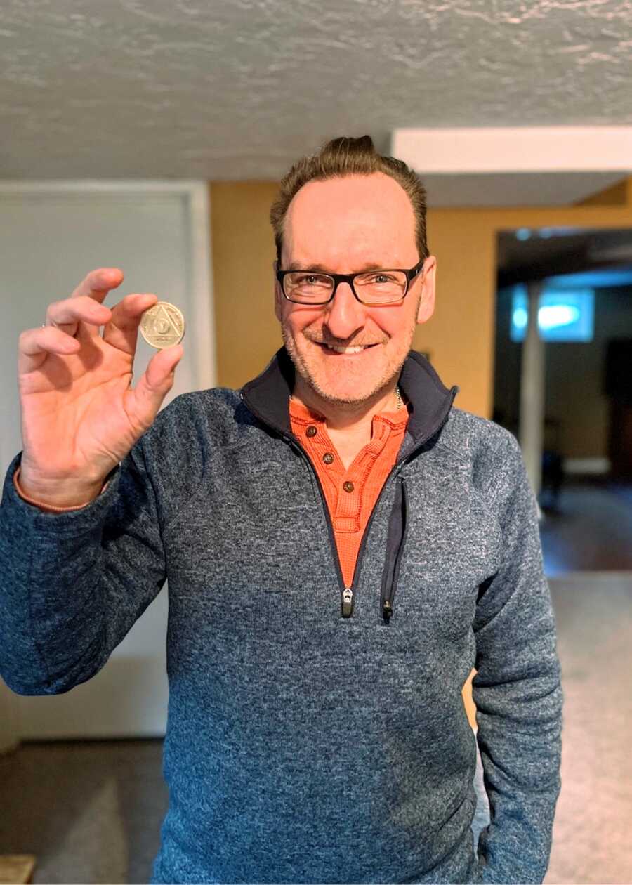 recovered alcoholic holds an Alcoholics Anonymous chip