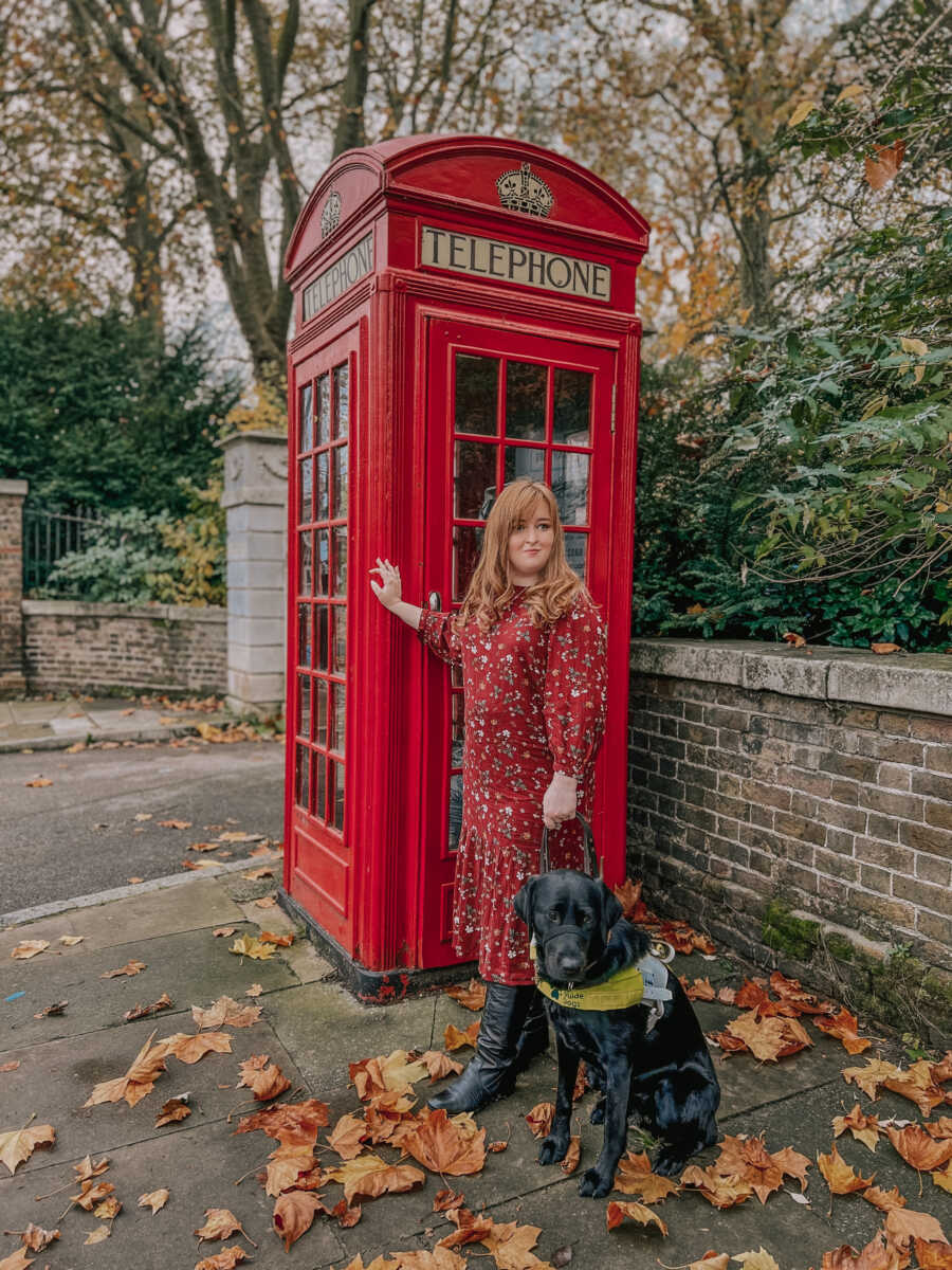 woman and guide dog at a phone booth