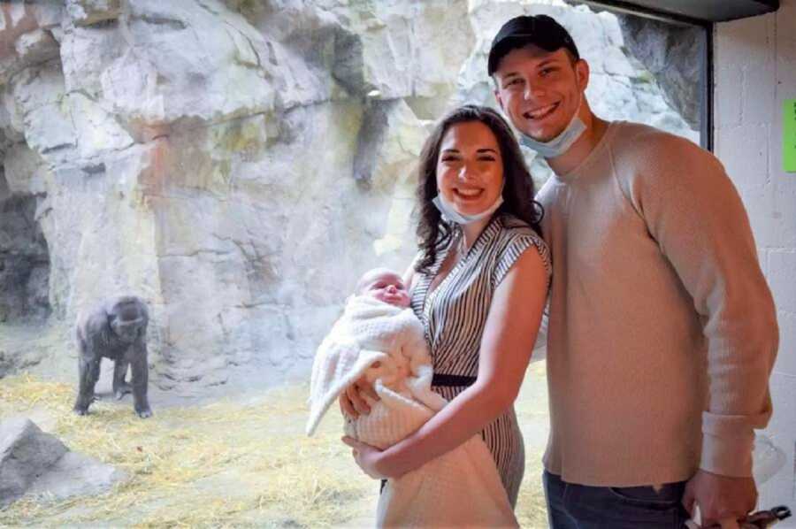 Young family takes picture in front of gorilla enclosure where they had incredible animal encounter. 