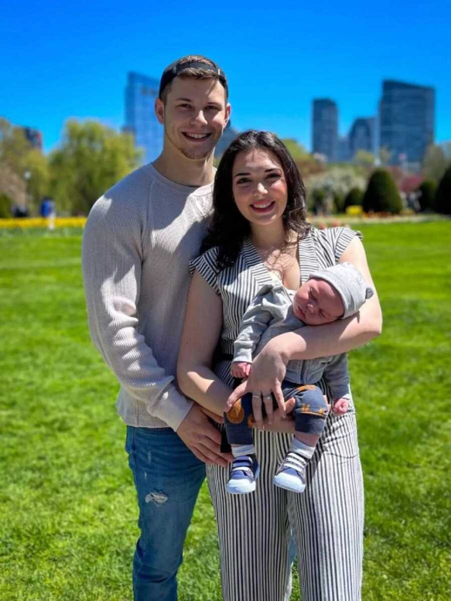 New parents take picture with newborn son on their trip to the zoo.