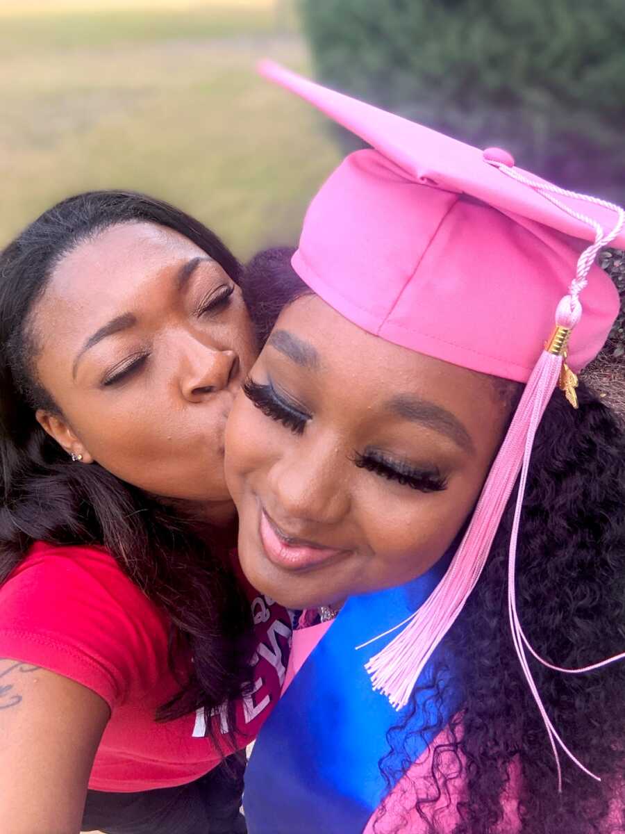 teen mom takes selfie with her daughter on her graduation day, kissing her cheek