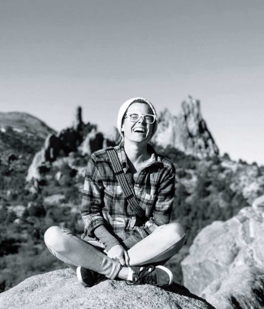 A mom siting cross-legged on a cliff