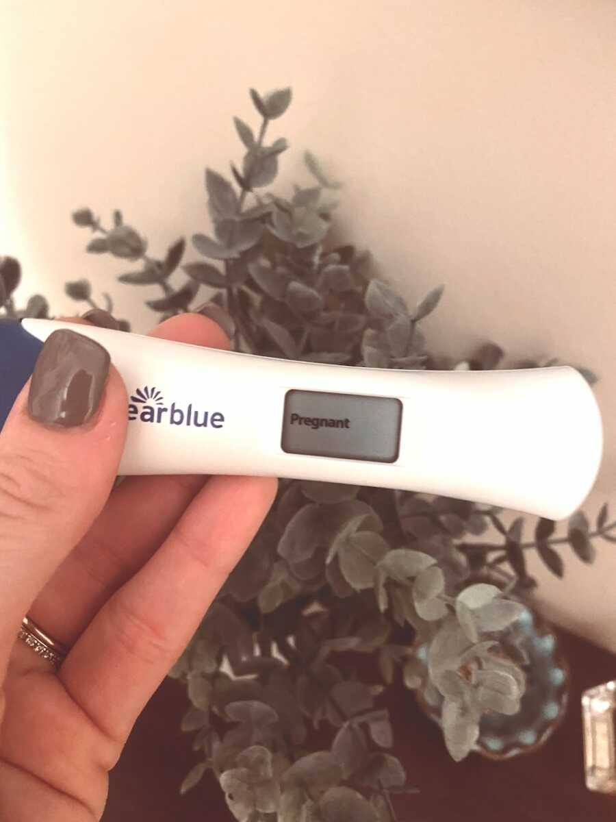 woman holds a digital pregnancy test in her hand with the screen saying "pregnant"