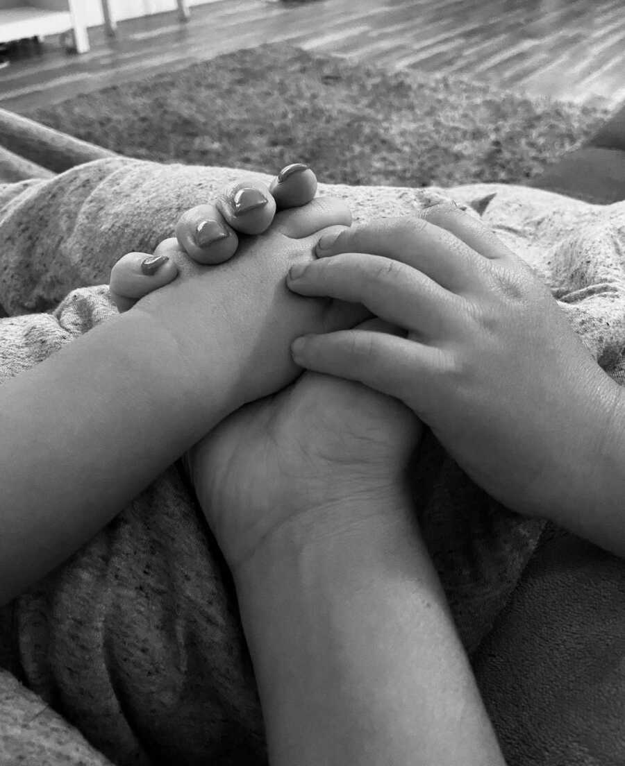 mother holds her hand out for her two children, all of them have their hands resting on each others