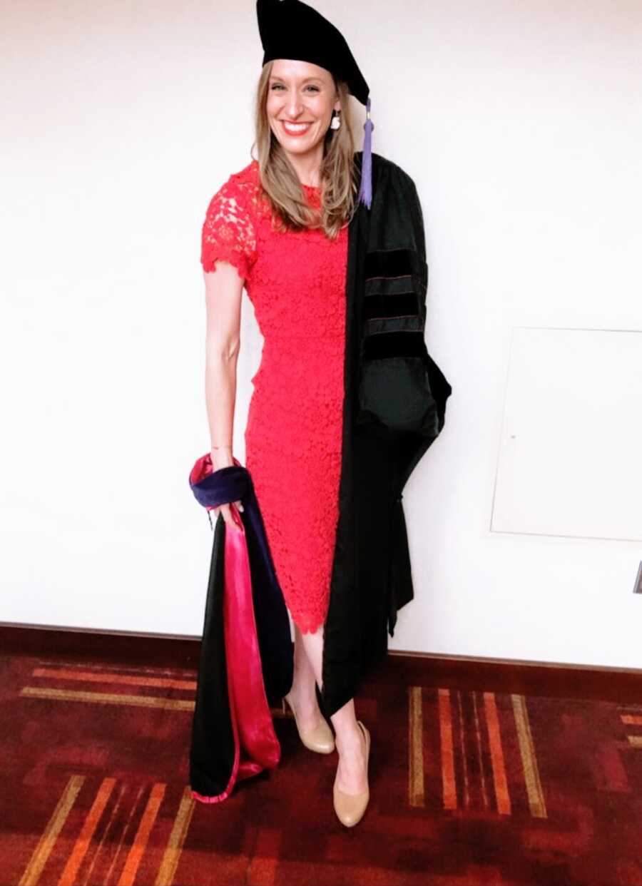 woman poses in her cap and gown for her graduation from law school