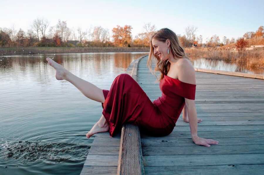 woman poses at a scenic lake and dips her toe into the water