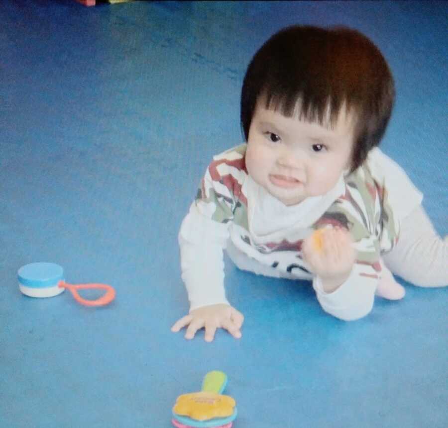 child who is up for adoption plays with children's toys while crawling on the floor