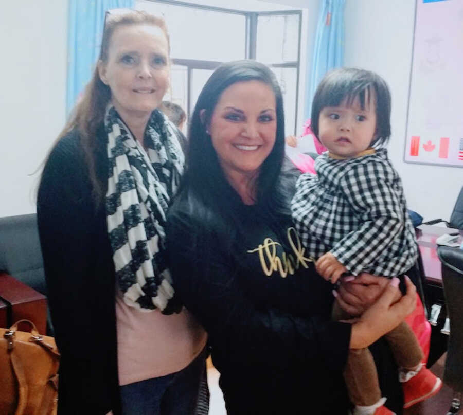 adoptive mother poses with her adopted daughter and the woman who helped her through the adoption process