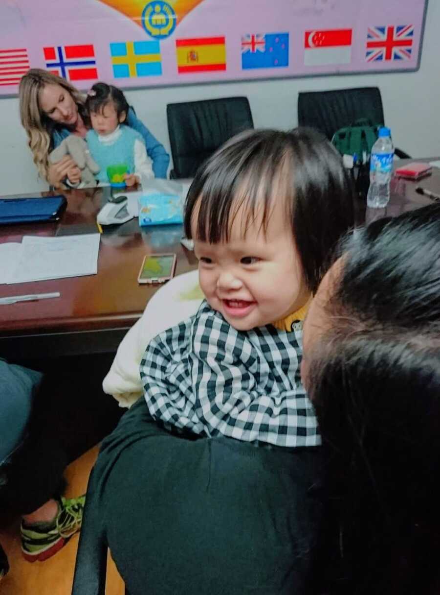 adoptive mother holds her child over her shoulder and consoles her