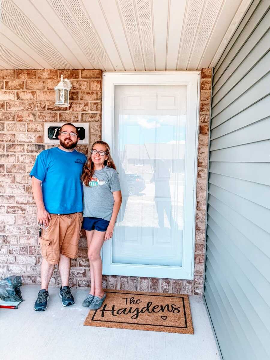 Couple take a photo on the porch of their first house they just purchased together