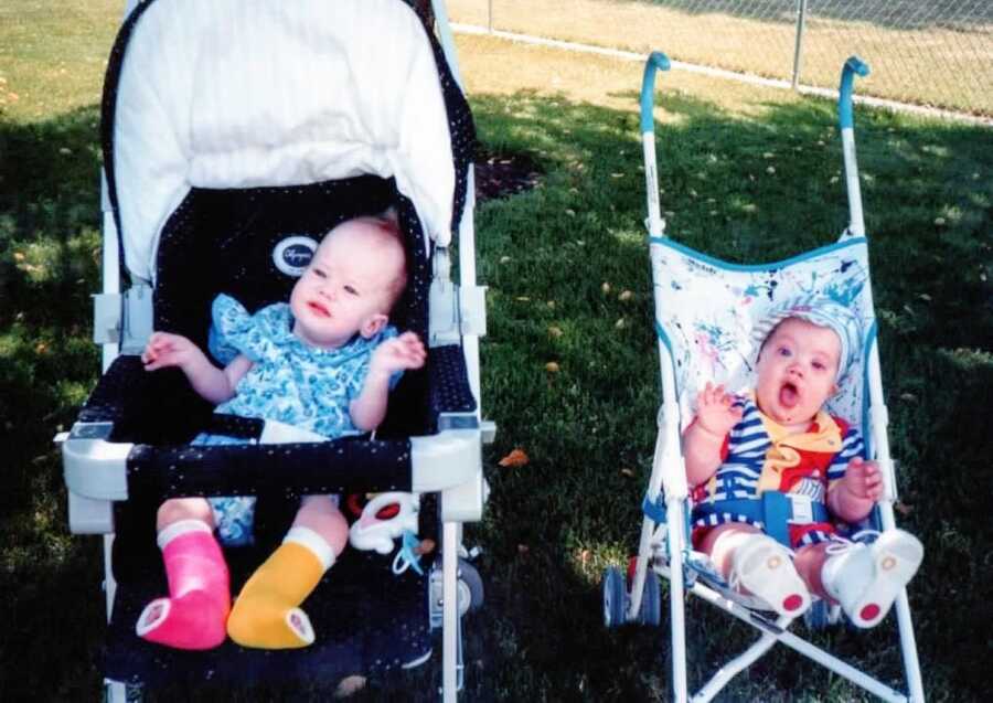 Little girl with unknown chronic illnesses sits in a stroller with colorful bandages wrapped around her legs