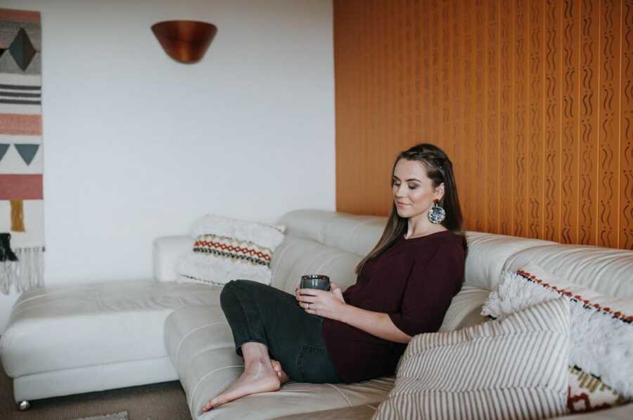 mom sits on her couch holding a cup