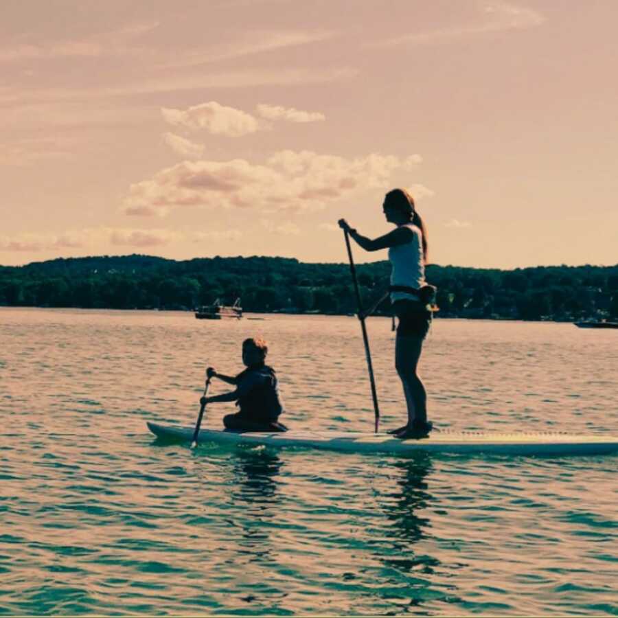 woman with her child on a paddle board in the lake