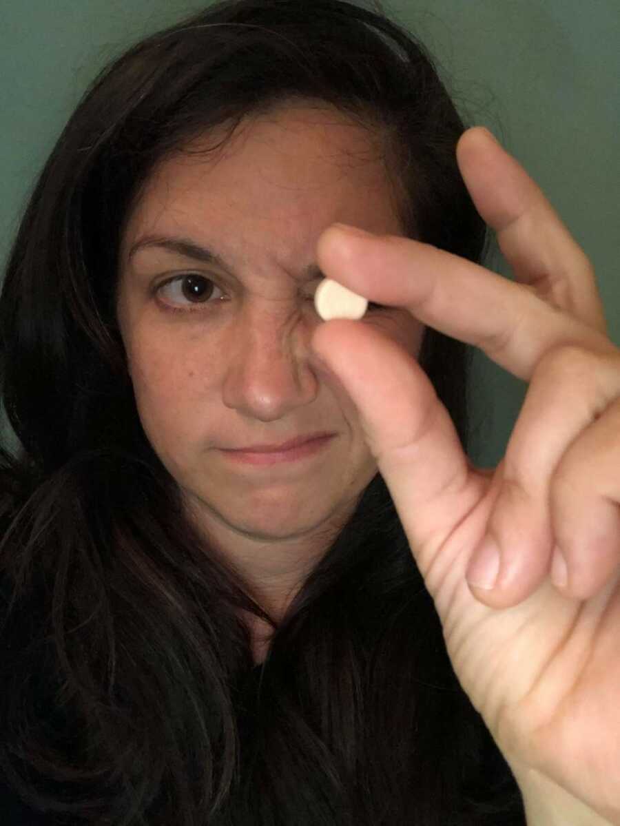 woman looking at her medication ready to take it