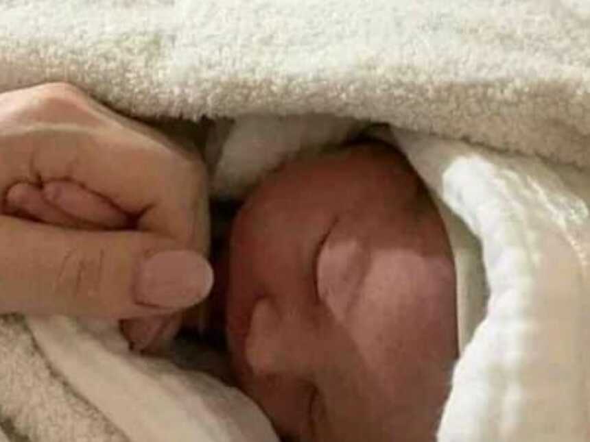 woman holding her new born baby's hand